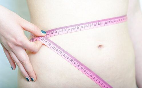 一名女孩测量自己的腰围，记录遵循杜坎饮食法的结果